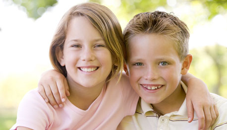 brother and sister smiling outside